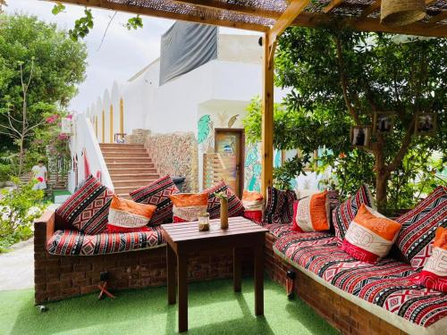 a patio with a couch with pillows and a table at Club Red Dahab Motel in Dahab