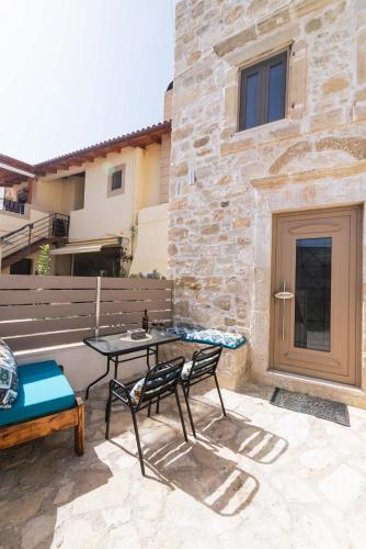 a patio with a table and a bench and a building at Faidra House in Vóroi
