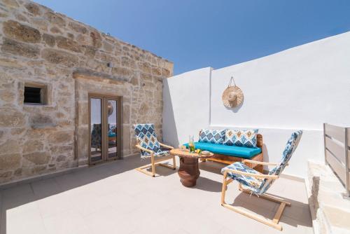 a patio with chairs and a couch and a table at Faidra House in Vóroi