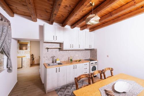 a kitchen with white cabinets and a table with chairs at Faidra House in Vóroi