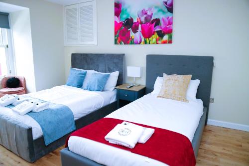 a bedroom with two beds and a painting on the wall at Bridge Street Guest Rooms in Tranent