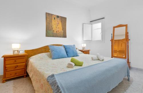 a bedroom with a bed with blue pillows and a mirror at Casita Isabella in El Golfo