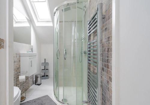 a glass shower in a bathroom with a brick wall at Blue Valley House in London