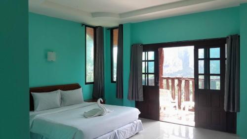 Garden View Resort Tonsai في شاطئ تونساي: غرفة نوم بجدران زرقاء وسرير عليه بجعة