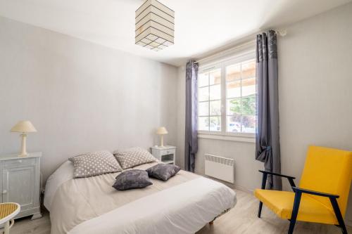 een slaapkamer met een bed en een gele stoel bij Villa de la mer - Bretignolles in Brétignolles-sur-Mer