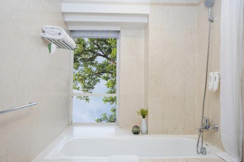 a bathroom with a shower and a tub with a window at Somerset Berlian Jakarta in Jakarta
