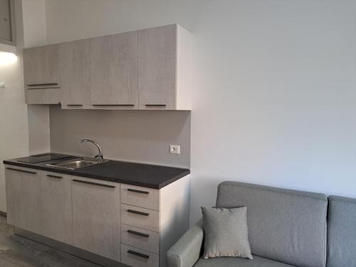 uma cozinha com um lavatório e um sofá num quarto em Monolocale 2\4 posti presso Residence la Spiaggia em Marotta