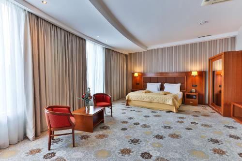 Kings Park Hotel في بودغوريتسا: غرفة فندقية بسرير وطاولة وكراسي