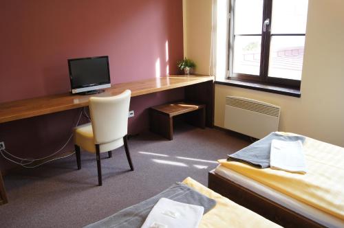 a room with a desk with a computer and a bed at Pension Inspirace a Wellness self check-in in Kolín