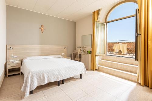 sypialnia z łóżkiem i dużym oknem w obiekcie Domus Pacis Assisi w Asyżu