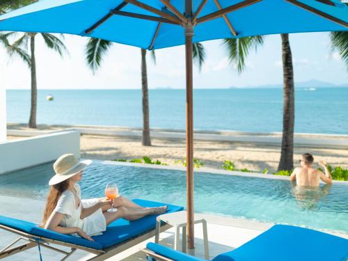 zwei Frauen auf Liegestühlen neben einem Pool in der Unterkunft Explorar Koh Samui - Adults Only Resort and Spa in Mae Nam