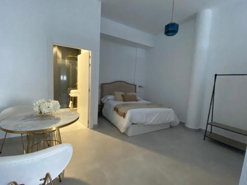 a white bedroom with a bed and a table at VETURIA APARTAMENTOS TURISTICOS in Mérida