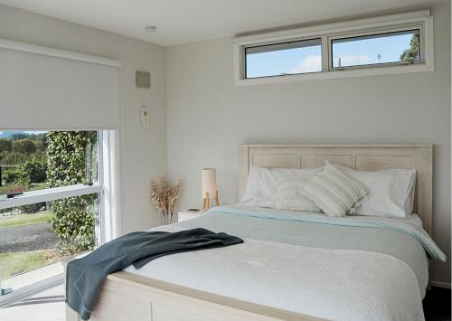 a white bedroom with a bed with a window at Minden Meadows Retreat in Tauranga