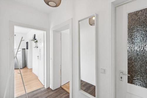 un couloir avec des murs blancs et un miroir dans l'établissement Worker Apartment Kleve, à Clèves