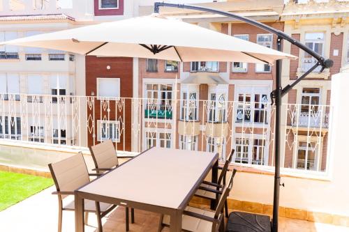 uma mesa e cadeiras debaixo de um guarda-sol numa varanda em Apartamentos Turísticos Gran Vía em Cartagena
