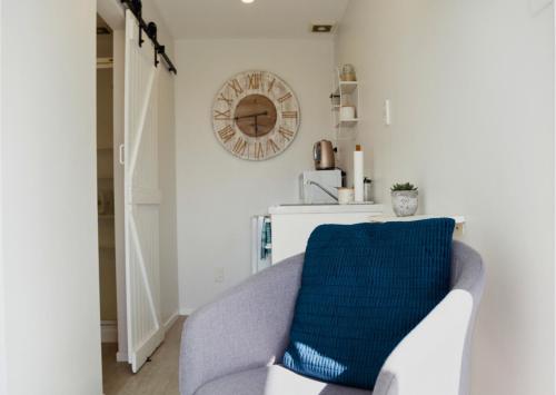 a living room with a chair and a clock on the wall at Minden Meadows Retreat in Tauranga