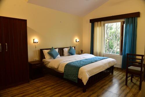 Un dormitorio con una cama con almohadas azules y una ventana en Corbett Wala Home Stay, en Rāmnagar