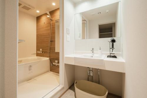 a bathroom with a sink and a shower and a toilet at Hotel Ninestates Kagoshima in Kagoshima