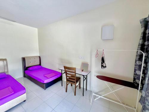 Habitación con 2 camas y mesa con colchón morado. en Roomstay Ehsan, en Pekan