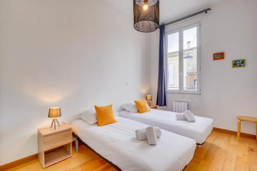 Dos camas en una habitación blanca con ventana. en Le Yellow - Centre de Bordeaux, en Burdeos