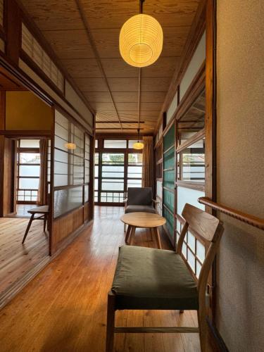 a room with a table and chairs and a lamp at 敷島旅館 in Saijo