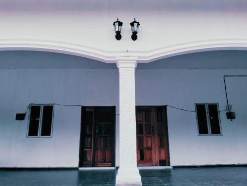 a large white building with a column and two windows at MTF Homestay in Baling