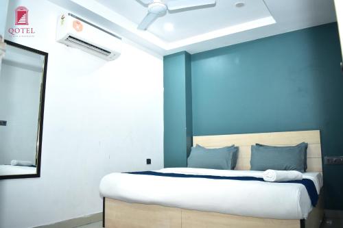 a bedroom with a bed with a blue wall at Qotel Hotel Rama Rohini Sector-24 Couple Friendly in New Delhi