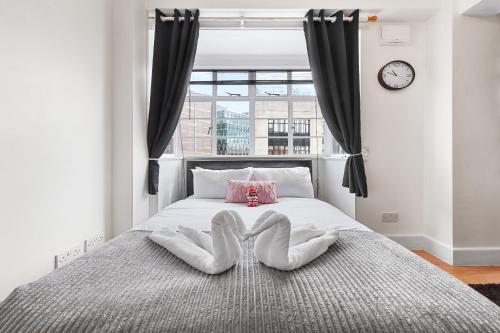 ein Schlafzimmer mit einem Bett mit zwei Handtüchern darauf in der Unterkunft Paddington Station Paradise for up to 4 Guests! Dream Apartment 2 mins walk from Station with extra double Sofa Bed! in London
