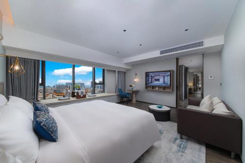 um quarto com uma grande cama branca e uma grande janela em Liz Hotel Maoming Dianbai em Maoming