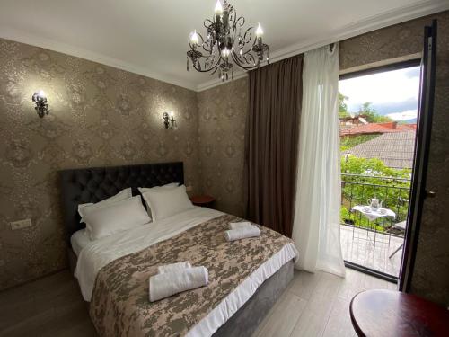 1 dormitorio con 1 cama con lámpara de araña y ventana en Sunny City en Borjomi