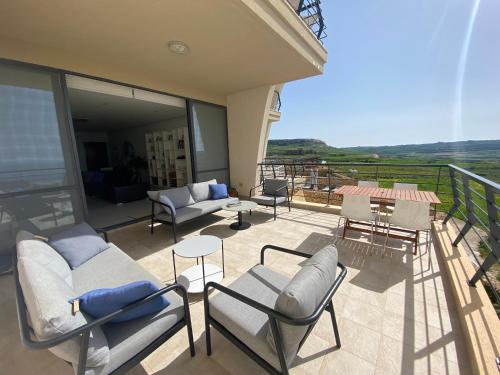 a balcony with chairs and a couch and tables at Gozo Dwejra Views in San Lawrenz