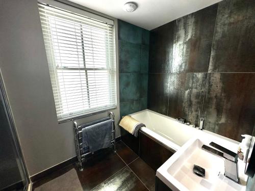 a bathroom with a tub and a sink and a window at 5 Bed Luxury House with Swimming pool in Chepstow