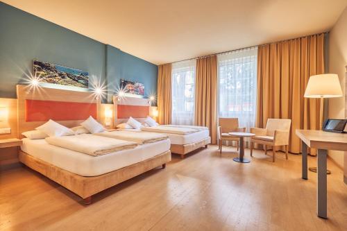 une chambre d'hôtel avec deux lits et un bureau dans l'établissement AKZENT Hotel Aufkirchen, à Aufkirchen