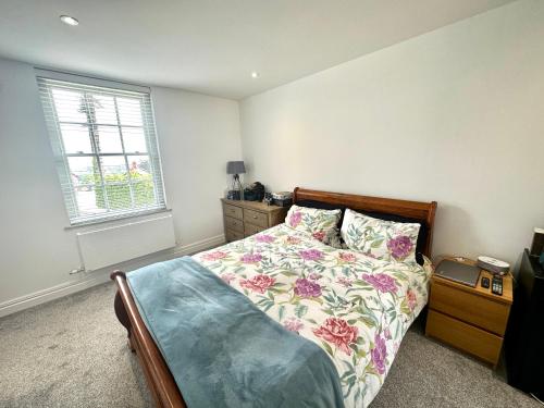a bedroom with a bed with a floral bedspread and a window at 5 Bed Luxury House with Swimming pool in Chepstow