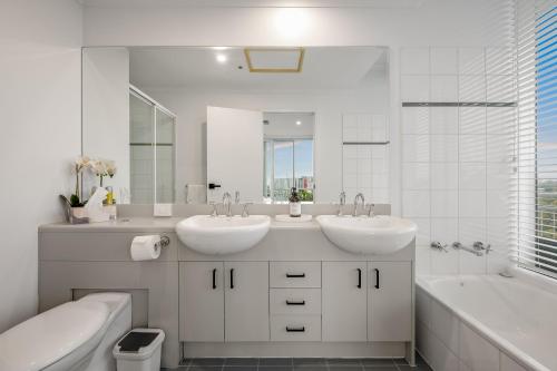 uma casa de banho branca com 2 lavatórios, uma banheira e um tubermott em Exclusive Stays - Southgate em Melbourne
