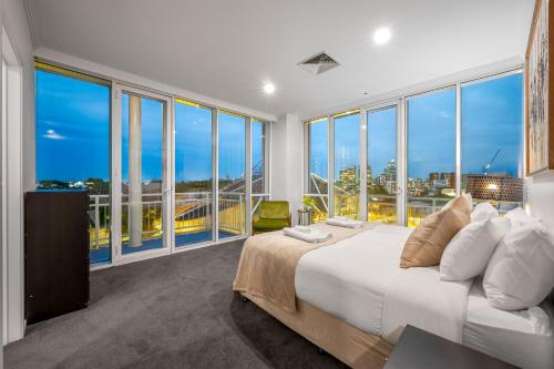 um quarto com uma cama grande e janelas grandes em Exclusive Stays - Southgate em Melbourne