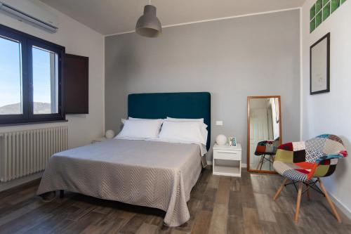 una camera da letto con un letto, una sedia e uno specchio di B&B Vignicella a Castelbuono