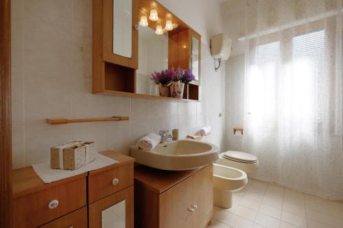 bagno con lavandino, servizi igienici e specchio di Casa Lucia a Teulada