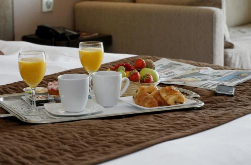 a tray with breakfast foods and two glasses of orange juice at Hôtel du Golf de l'Ailette, The Originals Relais in Chamouille