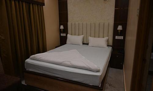 een slaapkamer met een bed met witte lakens en kussens bij FabHotel Granotel in kolkata