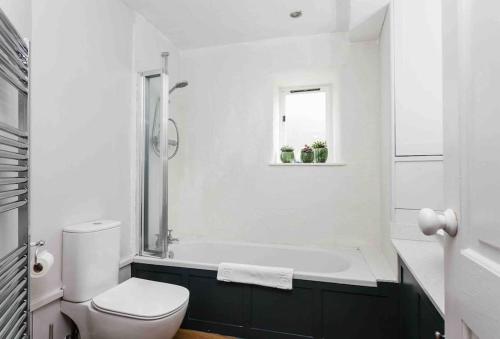 biała łazienka z wanną i toaletą w obiekcie A beautiful Cotswolds Cottage in Stroud w mieście Stroud