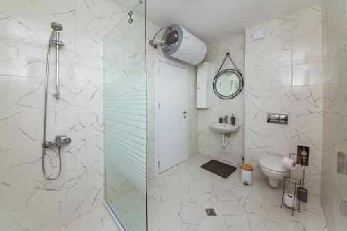 a bathroom with a shower and a toilet and a clock at AthmosphereVillaEma Apartments in Kranevo