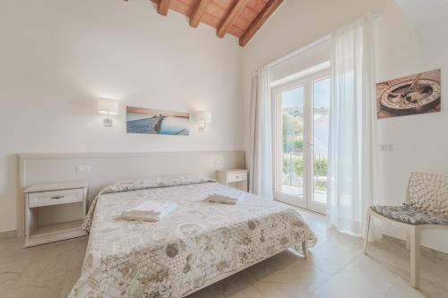 a white bedroom with a bed and a window at Villa Mia in Capoliveri