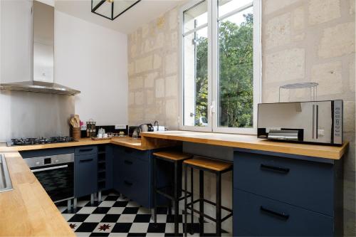 une cuisine avec des placards bleus et un sol en damier dans l'établissement Maison de maître proche Bordeaux, à Carignan