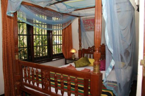 a bedroom with a wooden canopy bed with windows at Traditional Kandyan House in Kandy