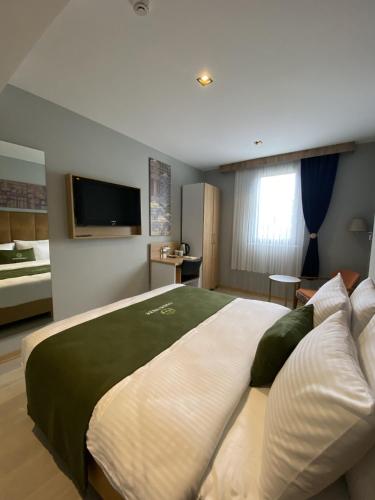 a bedroom with a large bed with a tv on the wall at Gardenmode Airport Hotel in Taşoluk