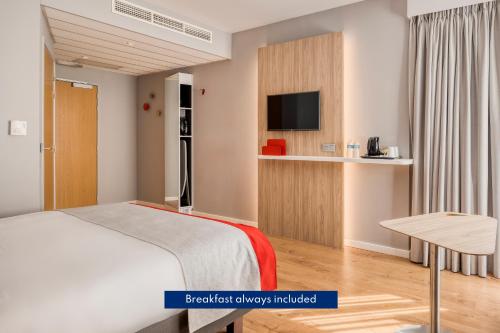 een slaapkamer met een bed en een televisie en een tafel bij Holiday Inn Express Mechelen City Centre, an IHG Hotel in Mechelen