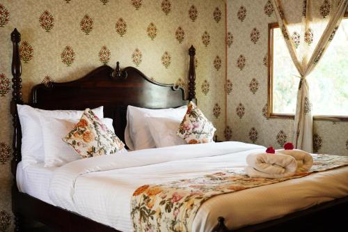 a bedroom with a bed with white sheets and a window at Heli Pushkar in Pushkar