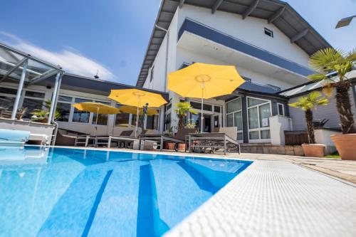 a swimming pool in front of a house with umbrellas at Hotel Landliebe in Söchau