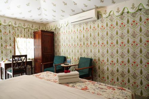 a bedroom with a bed and two chairs and a desk at Heli Pushkar in Pushkar